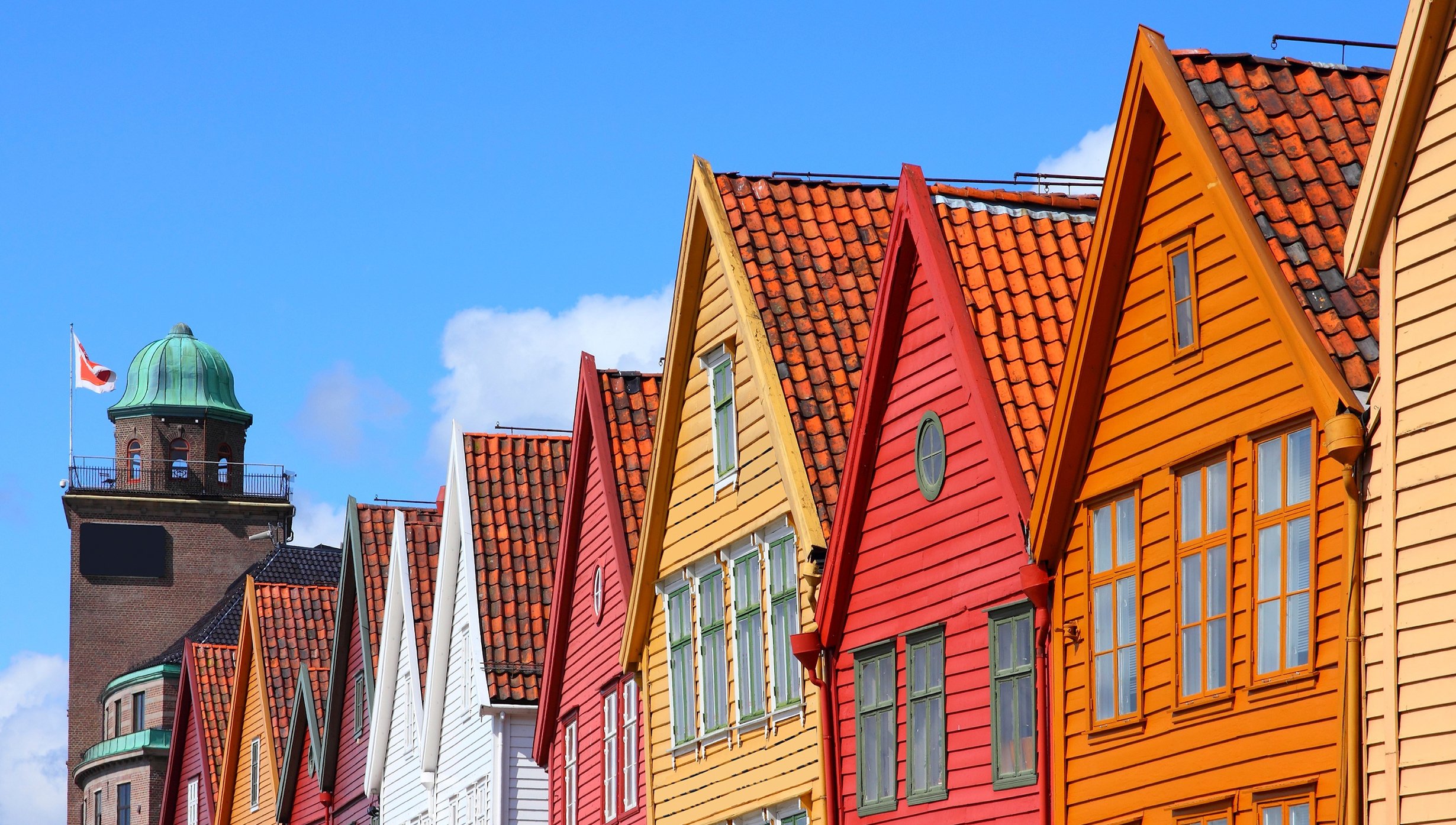 Colorful wooden houses in Bergen's historic Bryggen district under a clear blue sky | MSC Cruises Colorful wooden houses in Bergen's historic Bryggen district under a clear blue sky | MSC Cruises