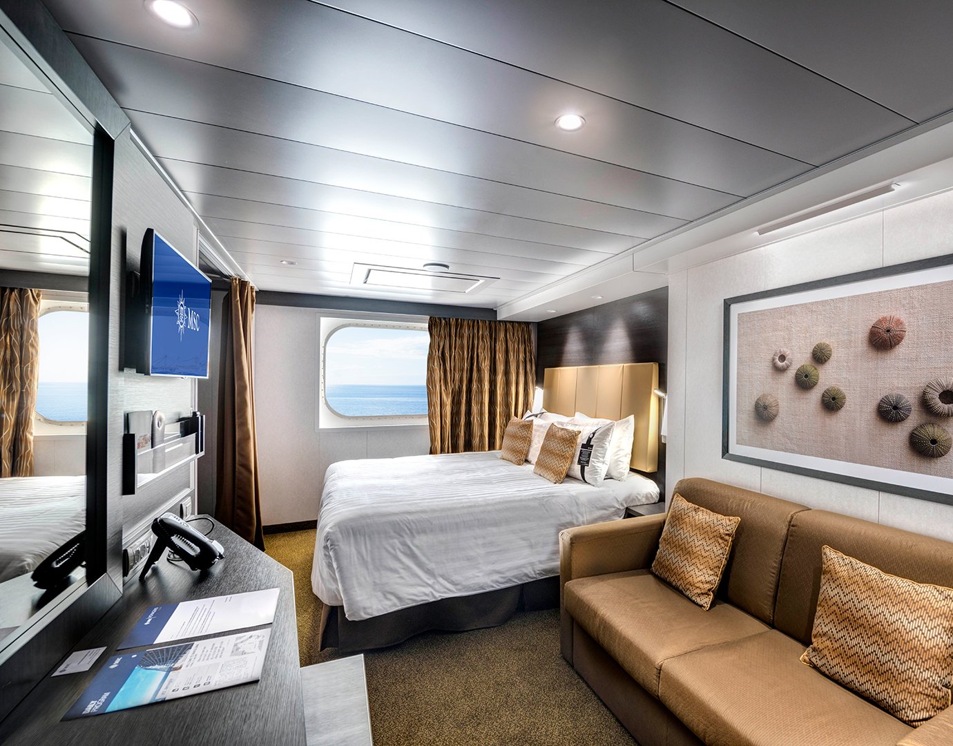 Spacious cruise ship cabin with ocean view, modern decor, and comfortable seating | MSC Cruises Spacious cruise ship cabin with ocean view, modern decor, and comfortable seating | MSC Cruises